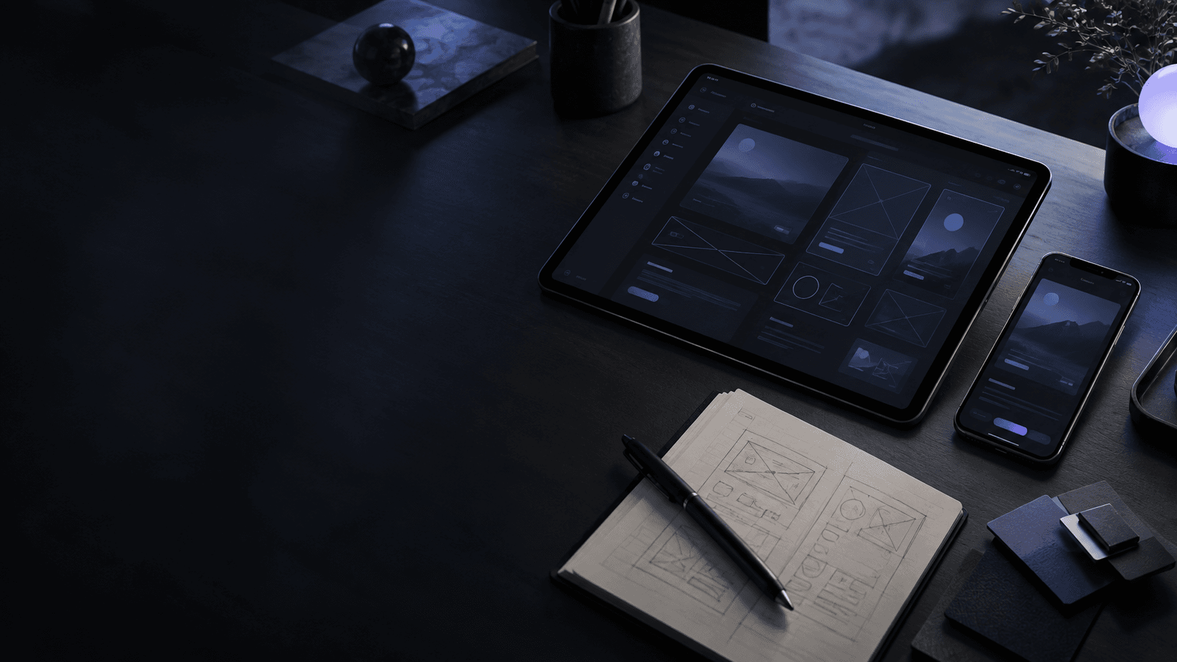 Tablet e celular exibindo protótipos de interface em uma mesa escura